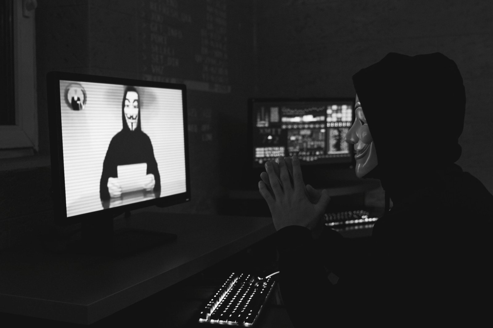 pexels-photo-5380681-5380681 Monochrome image of a masked hacker on a video call, showcasing cyber security themes.